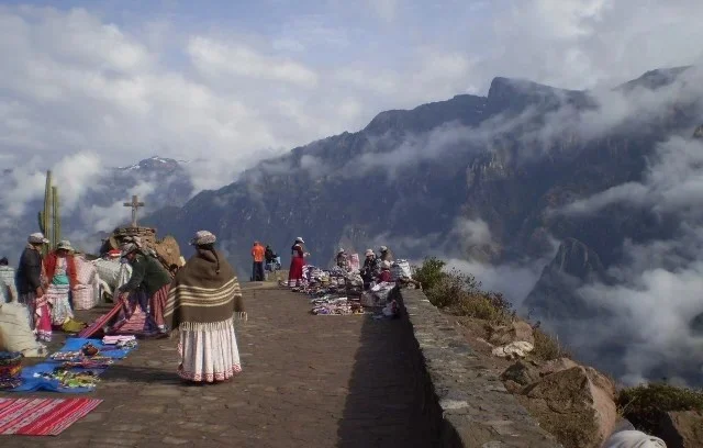 Puesto de artesanías tradicionales en el Cañón del Colca Mujeres con vestimenta tradicional venden artesanías en el mirador Cruz del Cóndor frente al Cañón del Colca