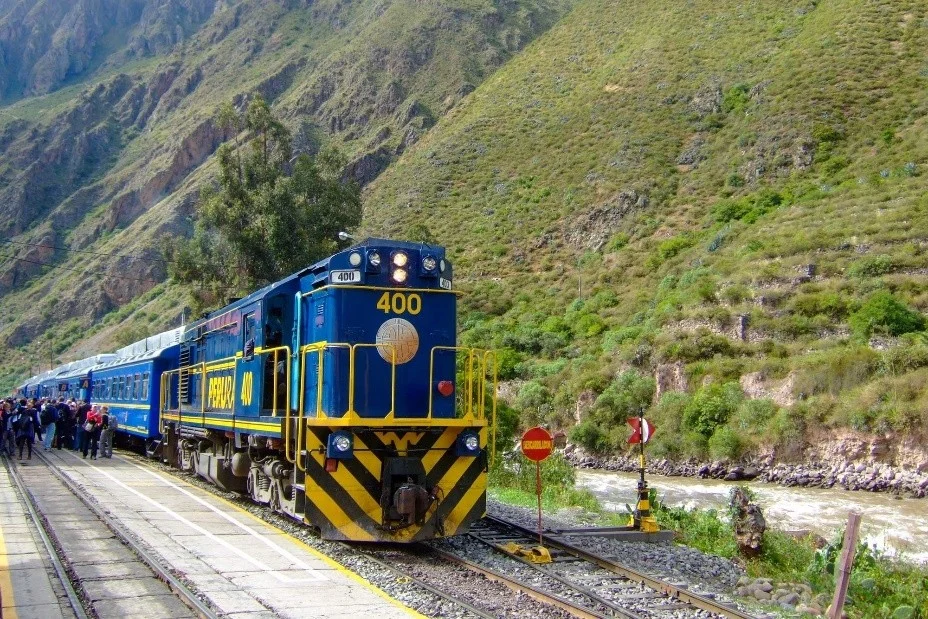 Ruta en tren PeruRail por el Valle Sagrado Tren azul de PeruRail con el número 400 detenido junto al río Urubamba y rodeado de montañas en el Valle Sagrado
